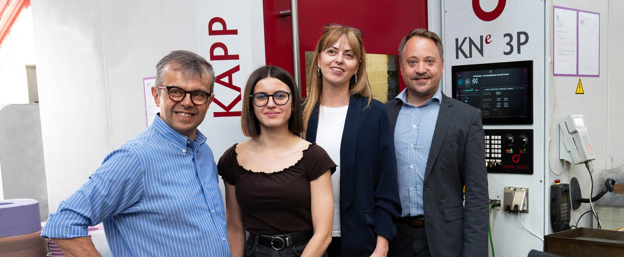 Michele und Giulia Resca (links) vor der Verzahnungs-Profilschleifmaschine KNe 3P, rechts daneben Chiara Crosta und Frank  Holzheid von Bitek.